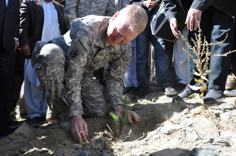 An Army officer planting a sapling.